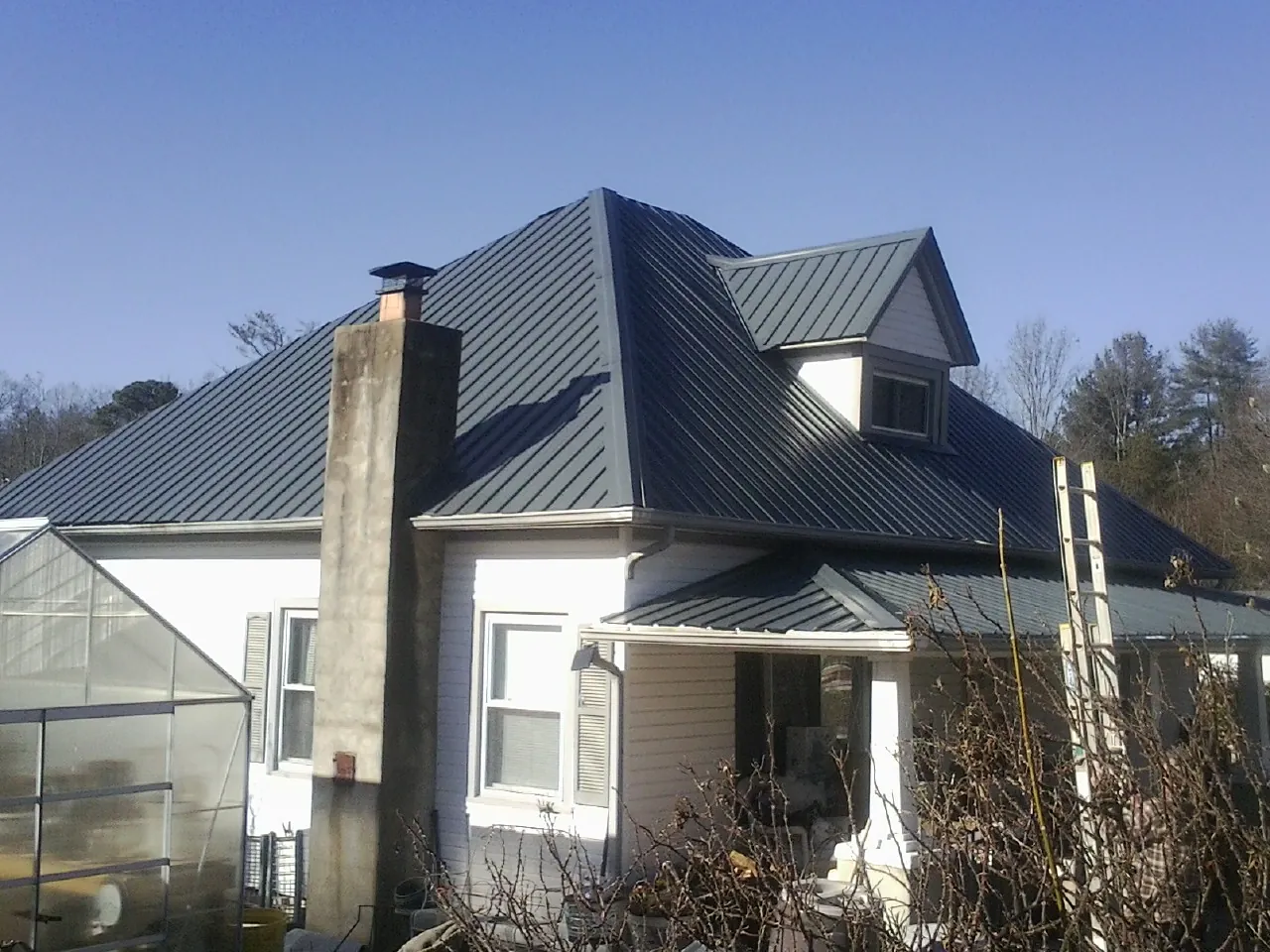 Dark blue standing seam metal roof on a white farmhouse with dormer — Slate & Tile Roof Repair by Roofing Brothers in Minneapolis