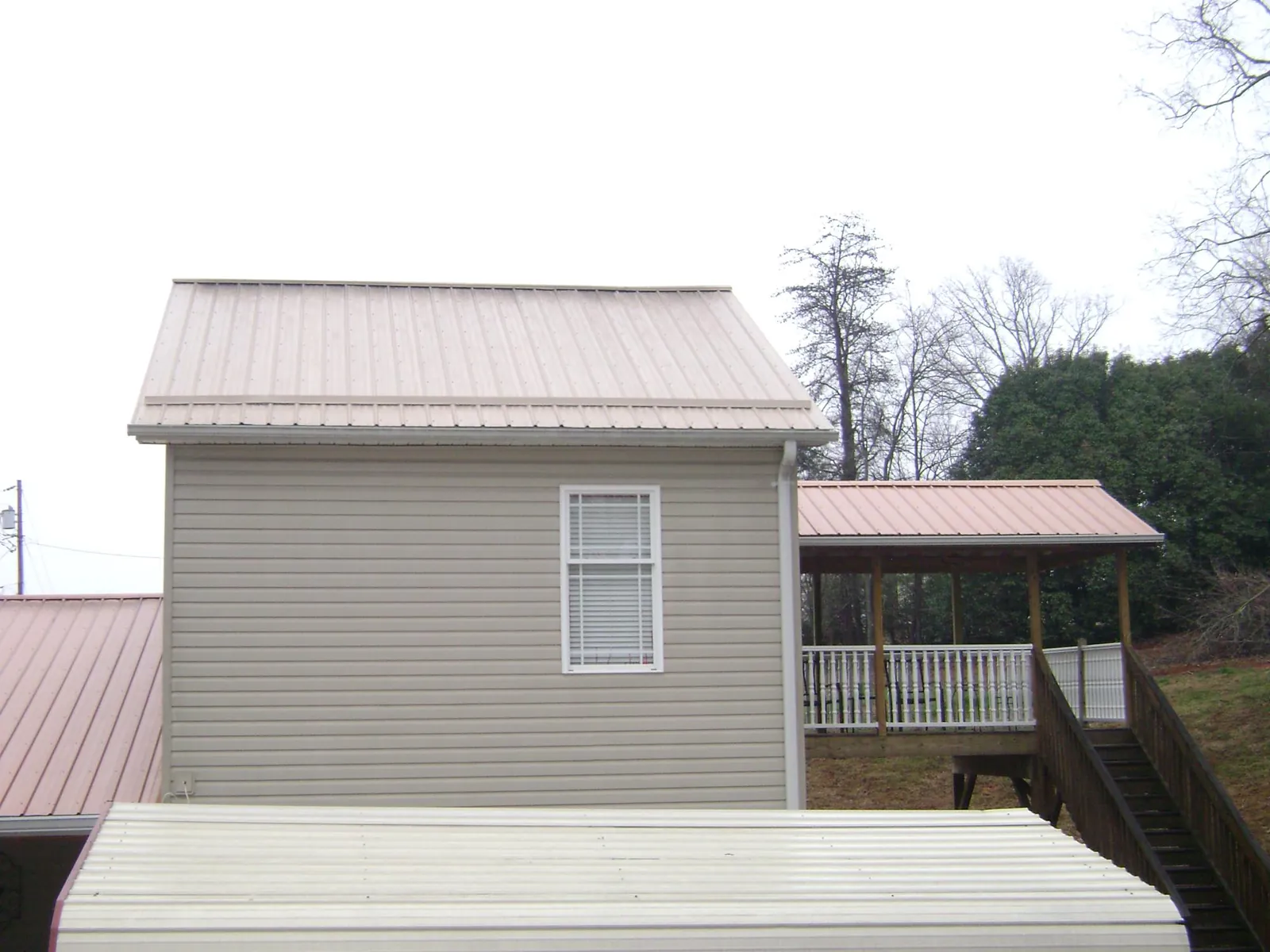 Tan metal roofs on a two story addition and attached porch, from a Roof Replacement job in Minneapolis